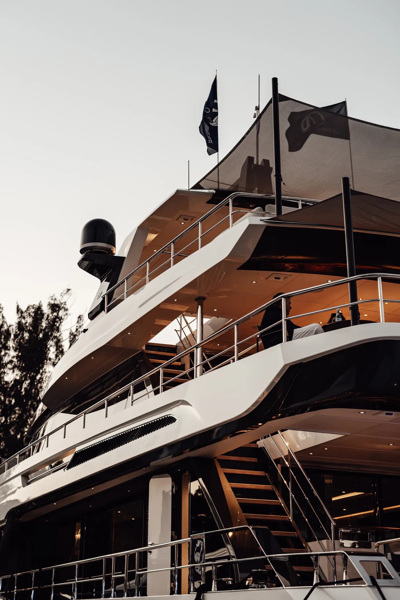 A multi-deck yacht at dusk with warm teak decks