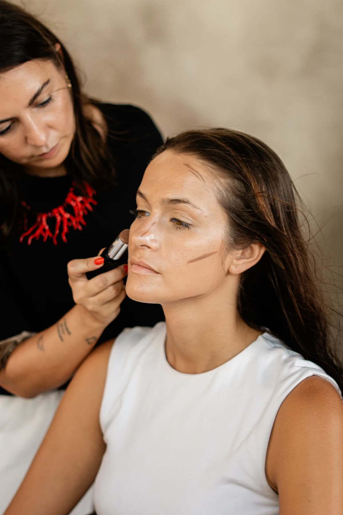 A makeup artist applying base to a model backstage