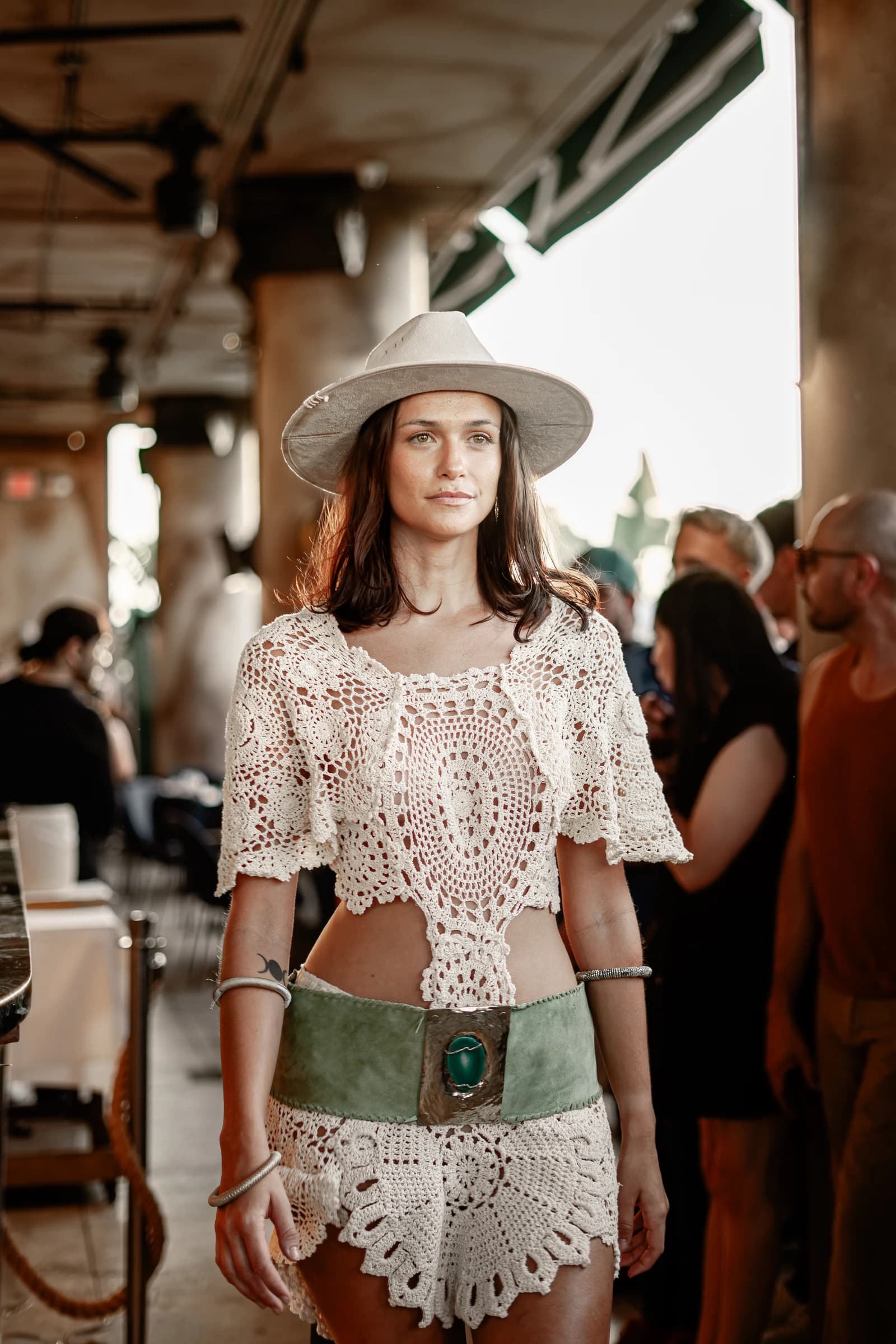 A model in a cream crochet outfit and wide-brim hat on the runway