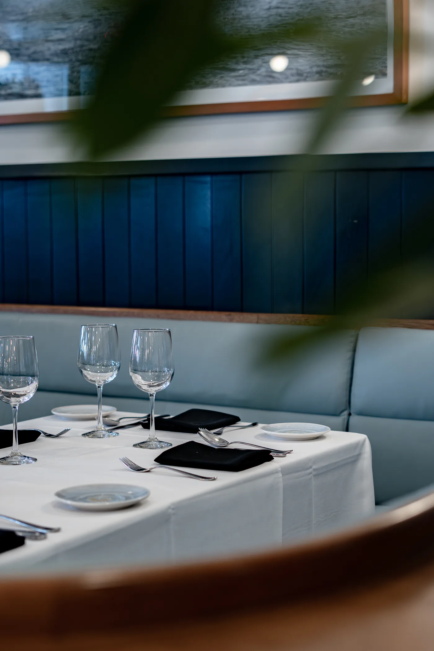 A banquette table set with wine glasses against blue panelling