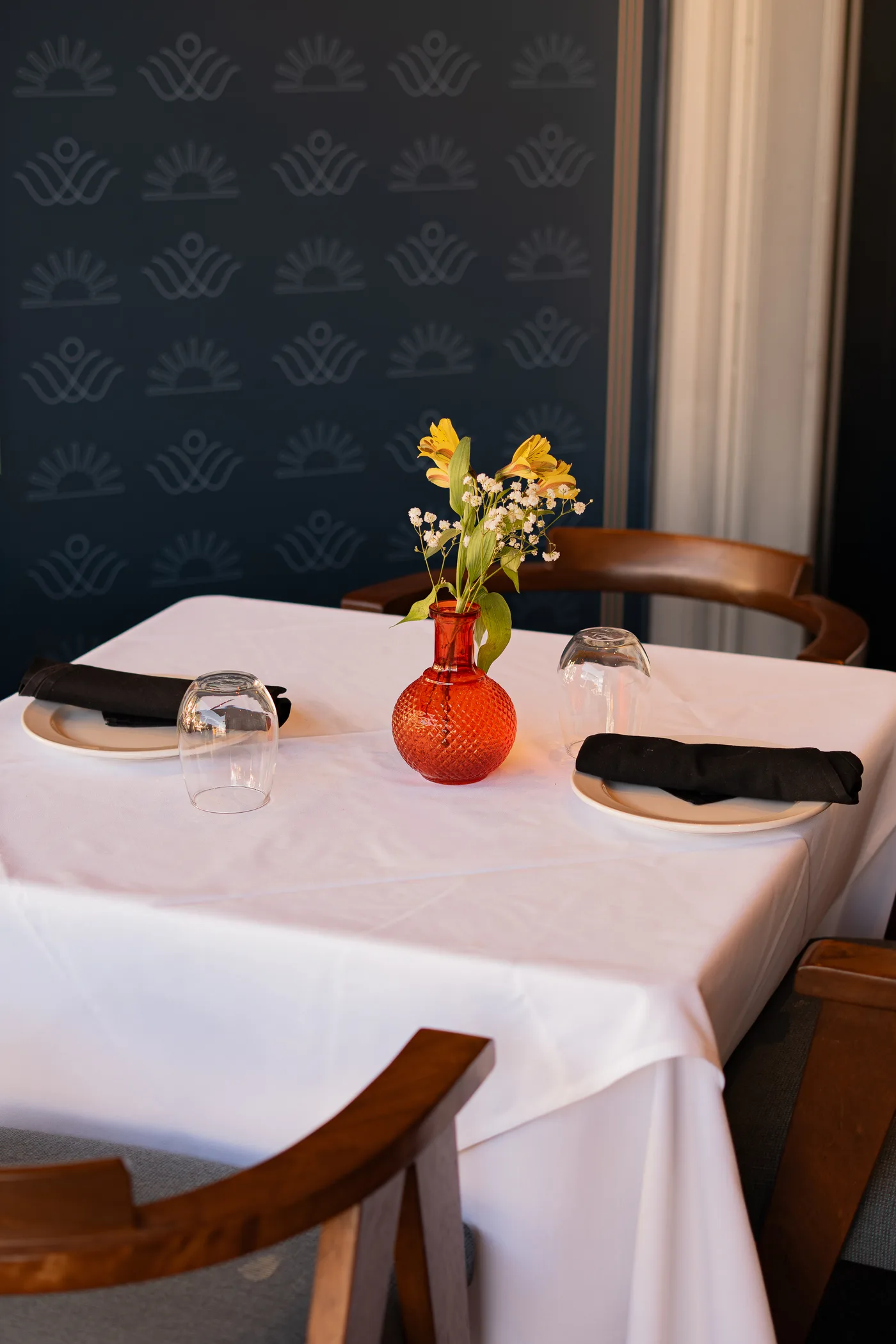 A set table with a red vase of yellow flowers