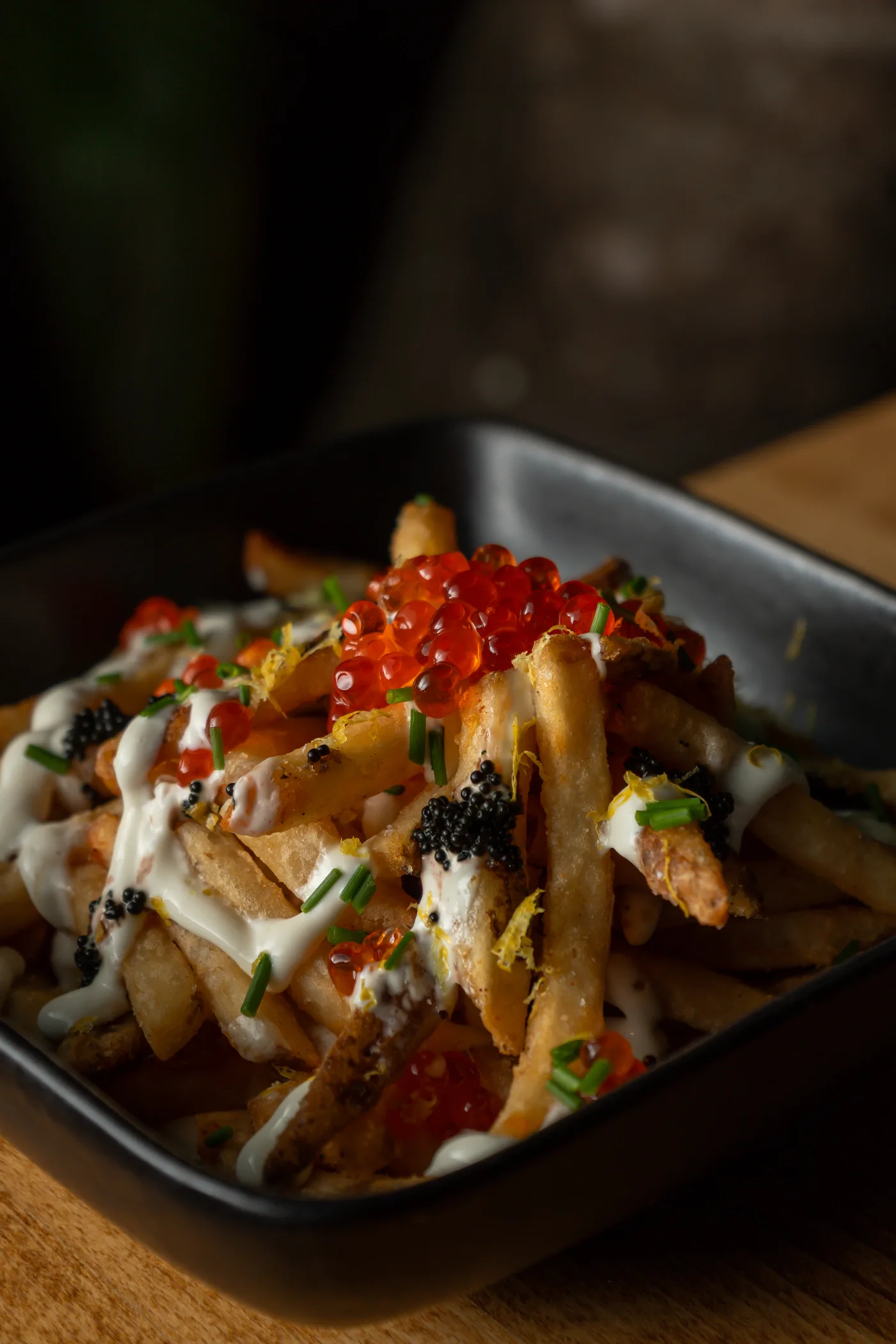 Loaded fries with salmon roe and caviar in a black dish