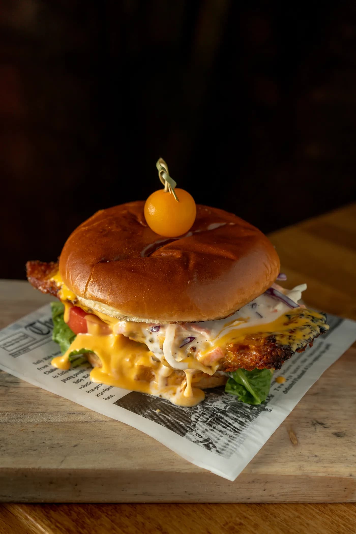 A stacked cheeseburger topped with a golden cherry