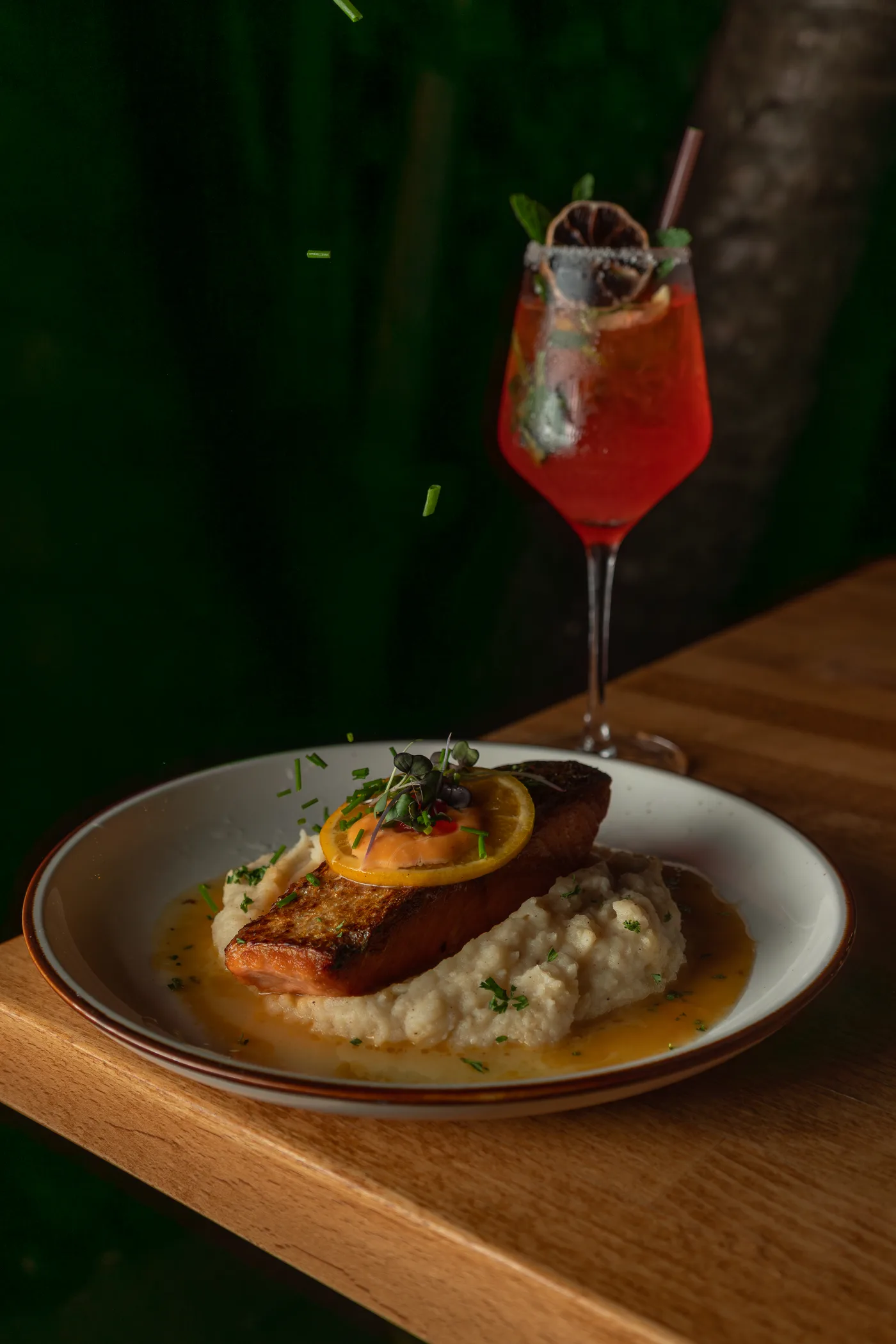 Crispy salmon over purée with a red spritz behind