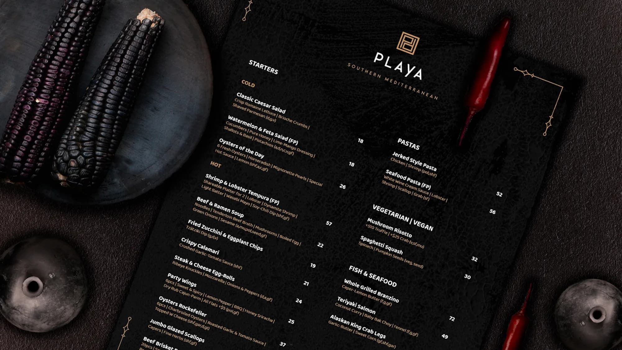 The Playa dark menu styled on a table with purple corn and chillies