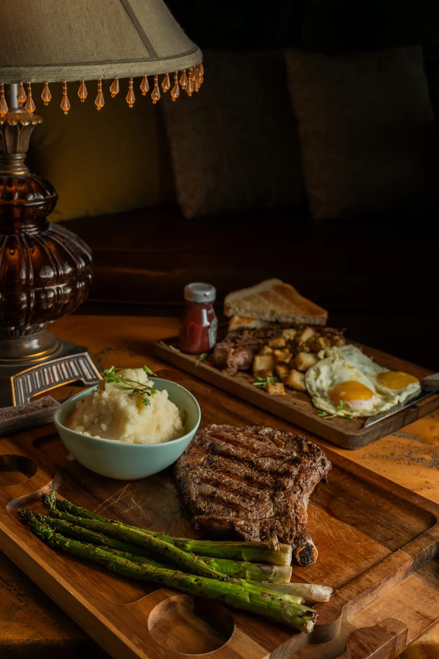 A grilled steak board with mashed potato, asparagus and eggs