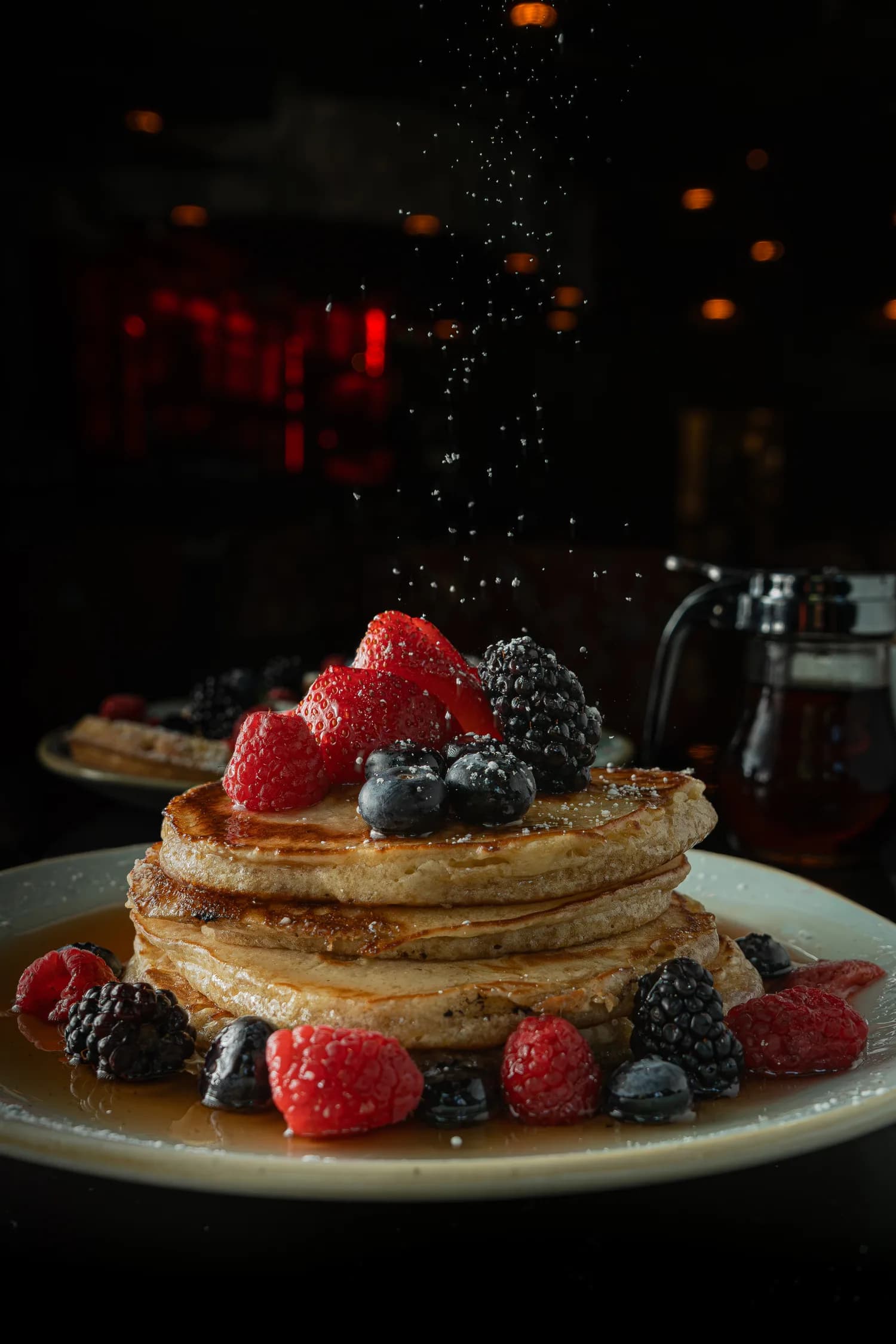 A stack of pancakes with berries and syrup